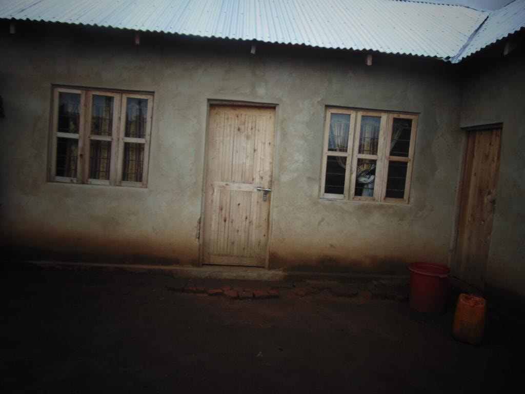 A completed Kuza Project house photographed at dusk with a motorbike parked outside