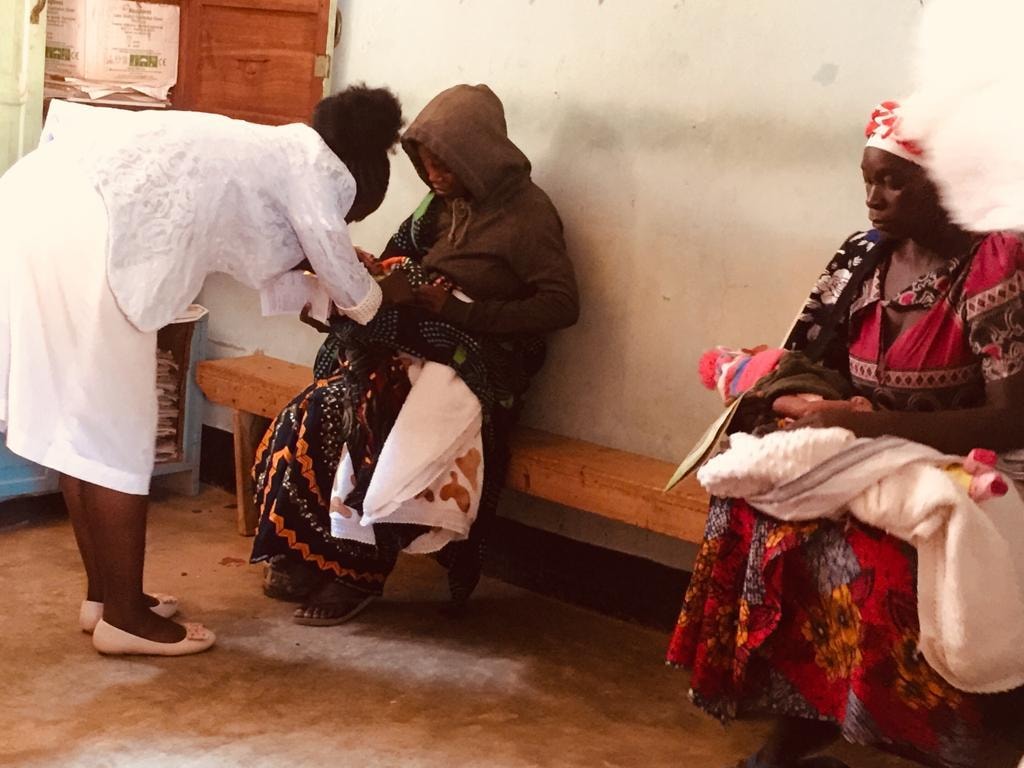 A nurse in close consultation with a mother holding her newborn baby at the RCH clinic in Njombe